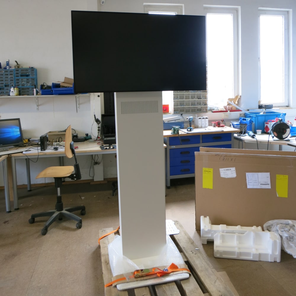 Monitor Standfuß und Display Standfuß Jamin (40 bis 55 Zoll, Querformat) in Signalweiß (RAL 9003) mit VESA-Schnittstelle, schwarzem Display, Lautsprechern und formschöner Bodenplatte.